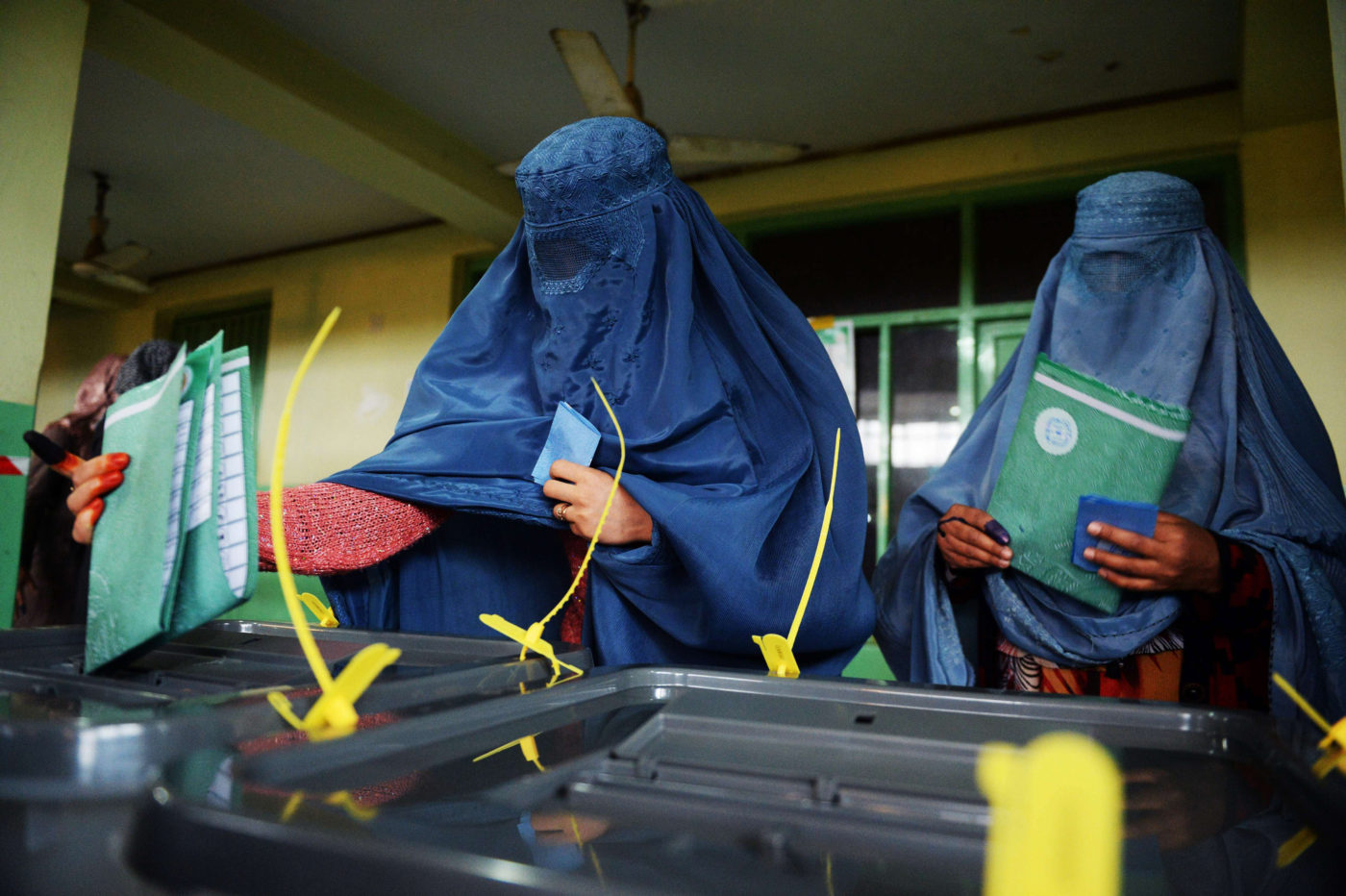 Kaksi siniseen burkhaan pukeutunutta naista jättävät äänensä äänestyslaatikkoon.