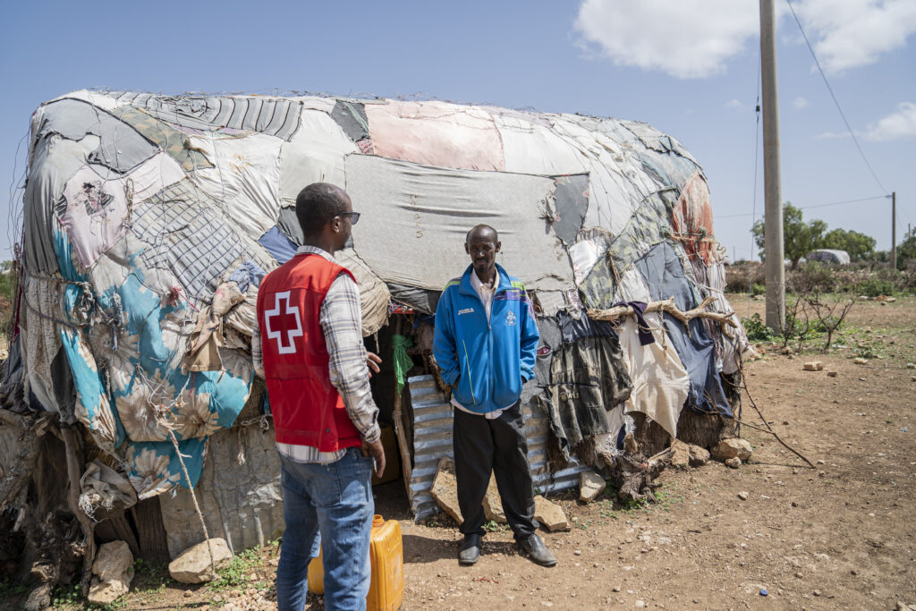 Kaksi etiopialaista miestä aaltolevyistä ja kangaspaloista rakennetun talon edessä.