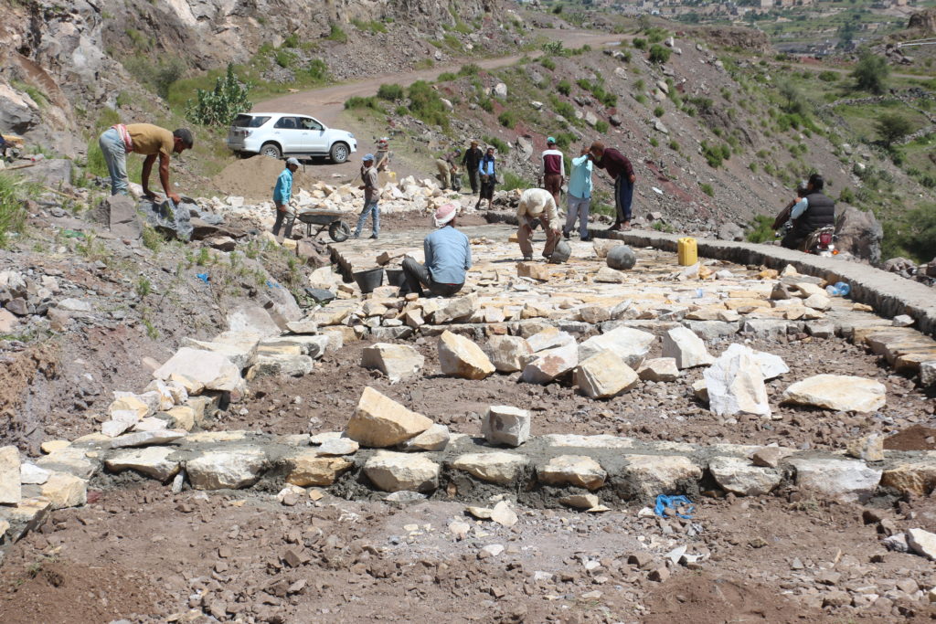 Miehiä latomassa kiviä maaseututietä rakennettaessa.