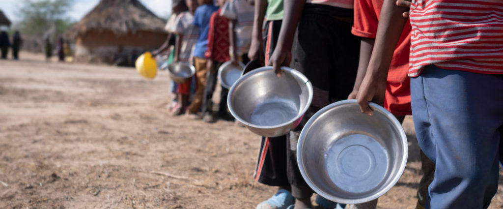Lapset jonottavat ruoka-apua käsissään peltiset ruoka-astiat.