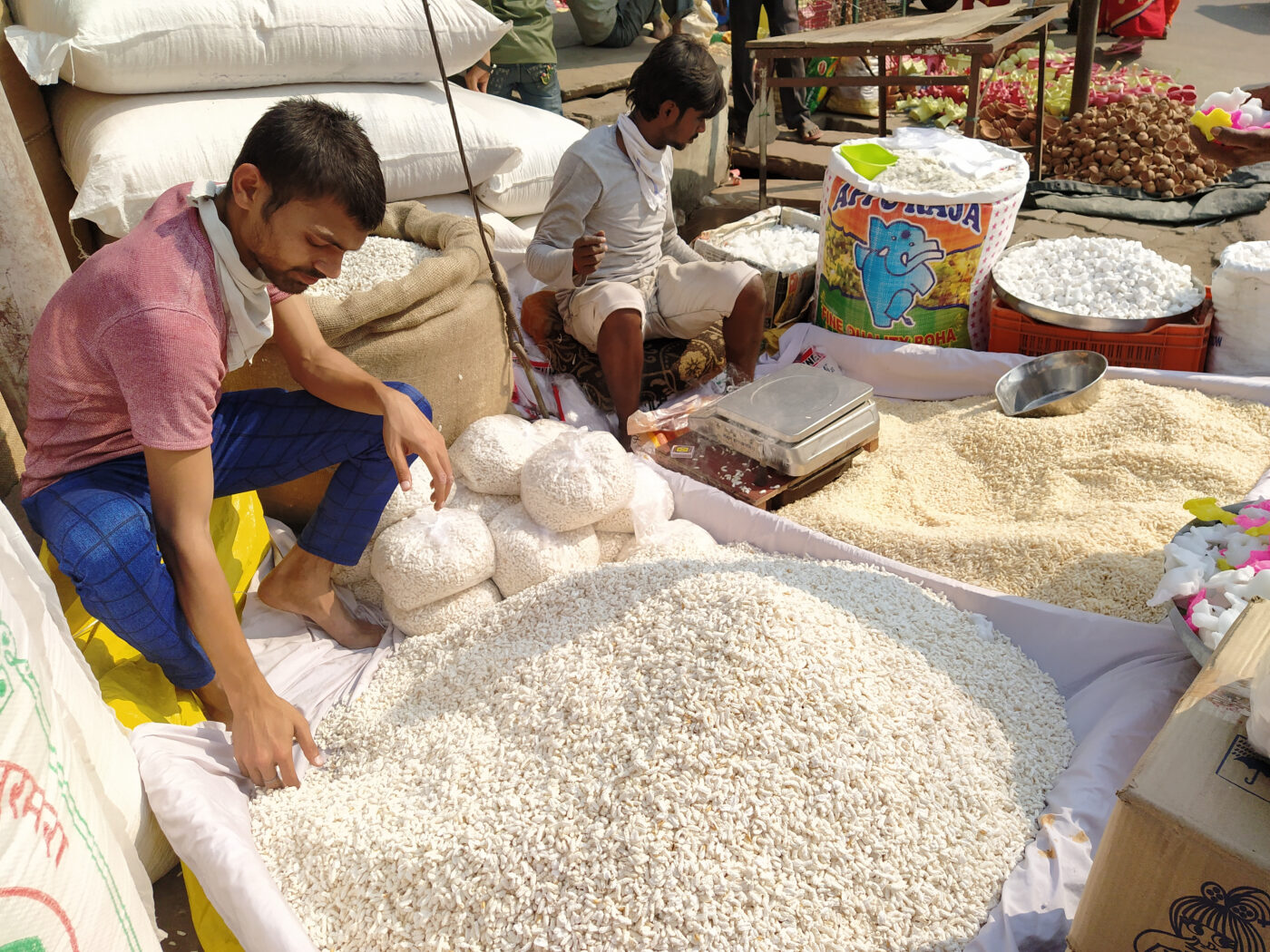 Kaksi henkilöä myyvät isoista säkeistä riisiä intialaisella ulkoilmatorilla.