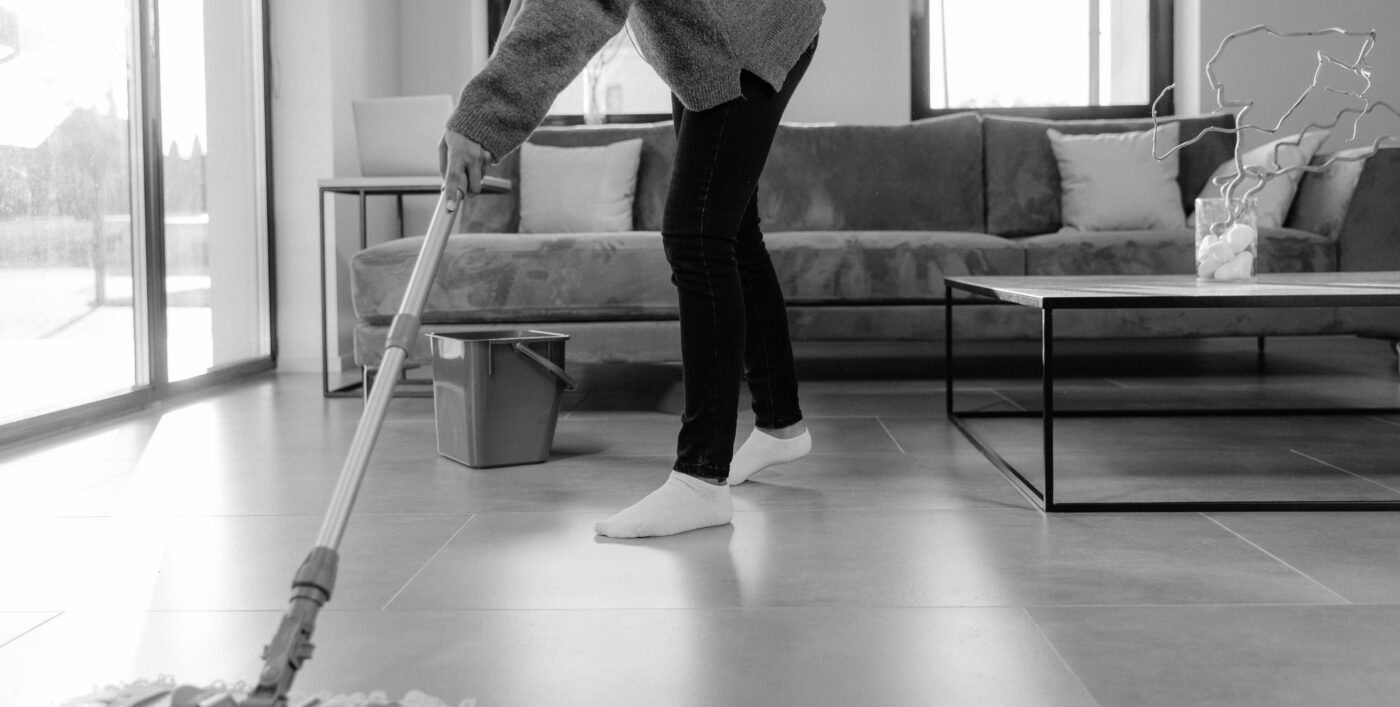 Mustavalkoinen kuva ihmisestä moppaamassa lattiaa.