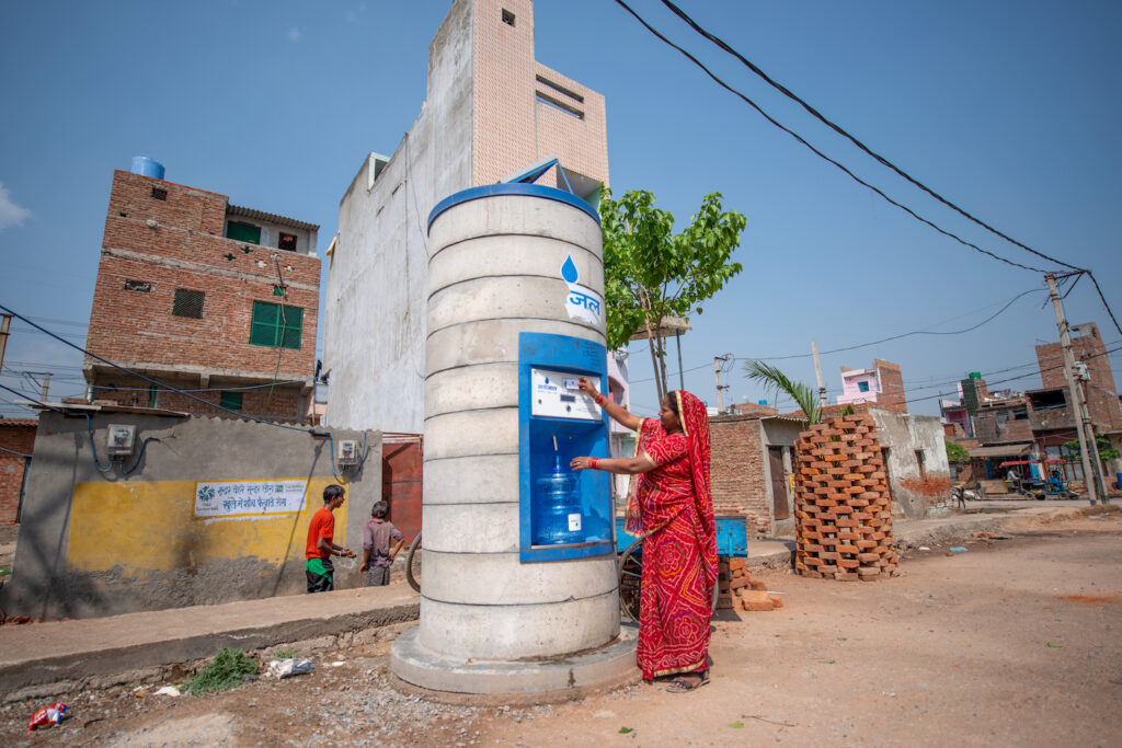 Punaiseen sariin pukeutunut nainen täyttää vesikanisteria vesiautomaatista.