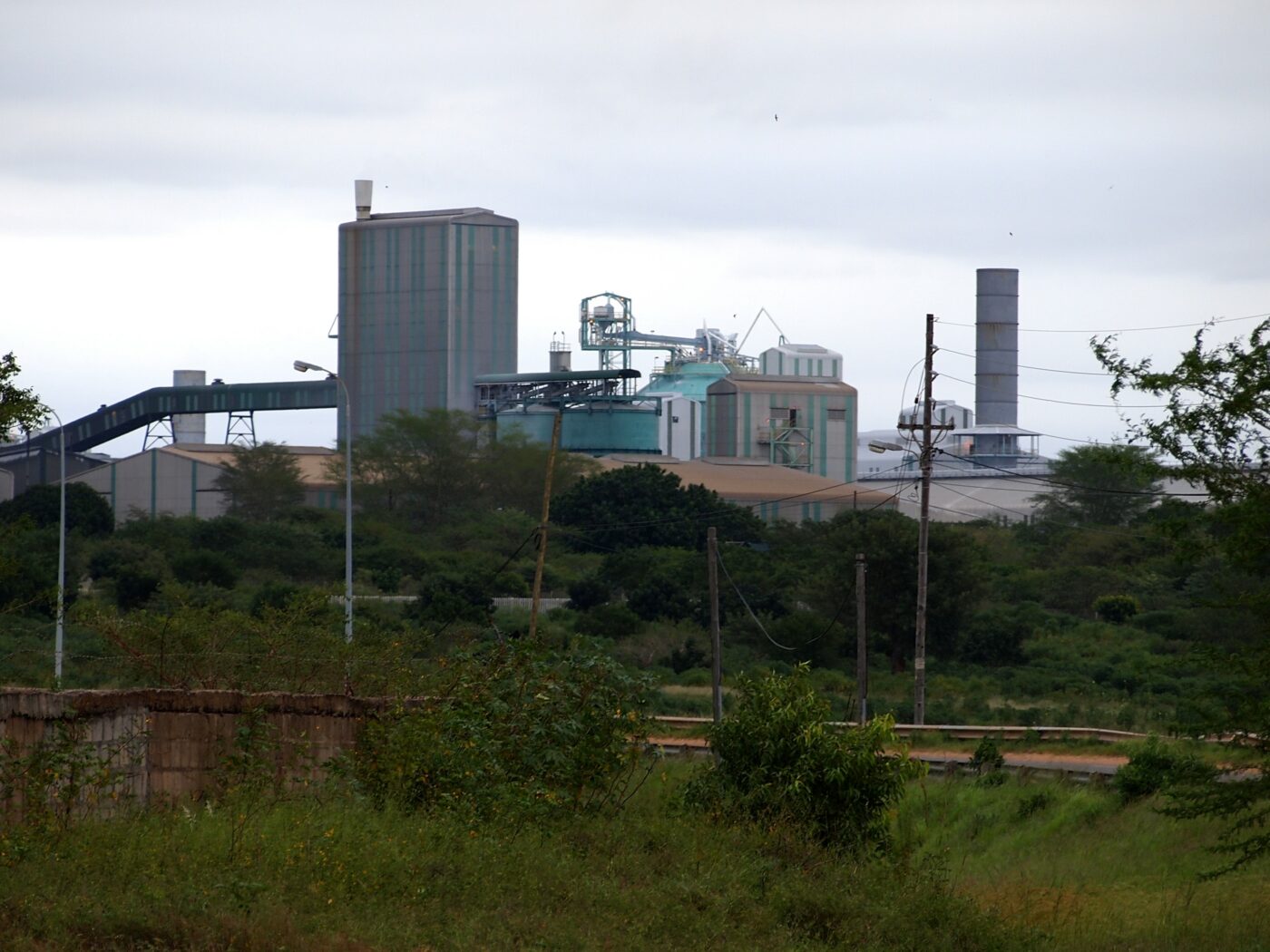 Iso teollisuuslaitos, taustalla taivasta, etualalla vihreää