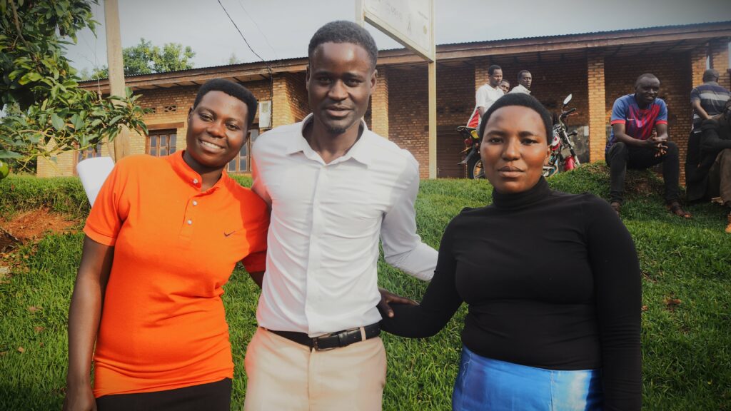 Kolme afrikkalaista nuorta ihmistä, yhdellä oranssi, yhdellä valkea, yhdellä musta paita.