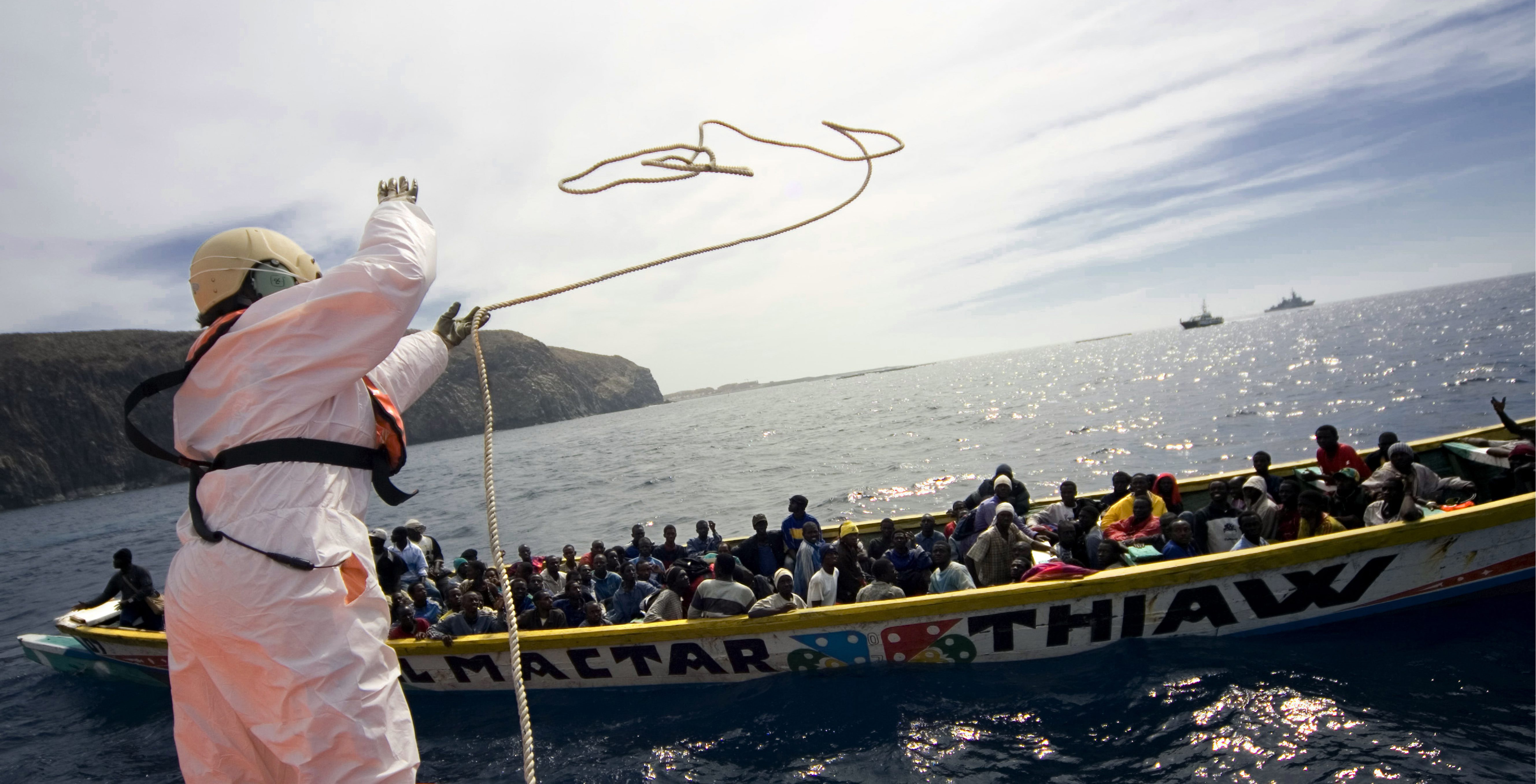 Espanjan rajavartiosto heittää köyden siirtolaisten veneeseen.